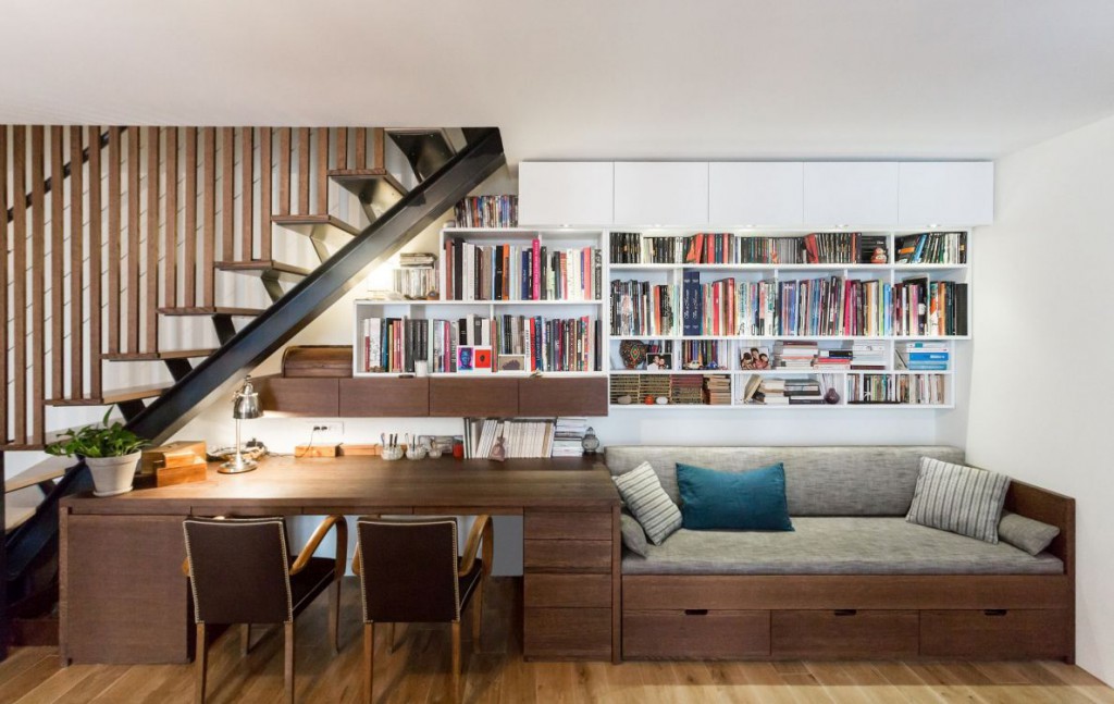 sous l'escalier une bibliotheque avec table et banquette, tout en bois sur mesure pour le sejour dans un apartement Parisien